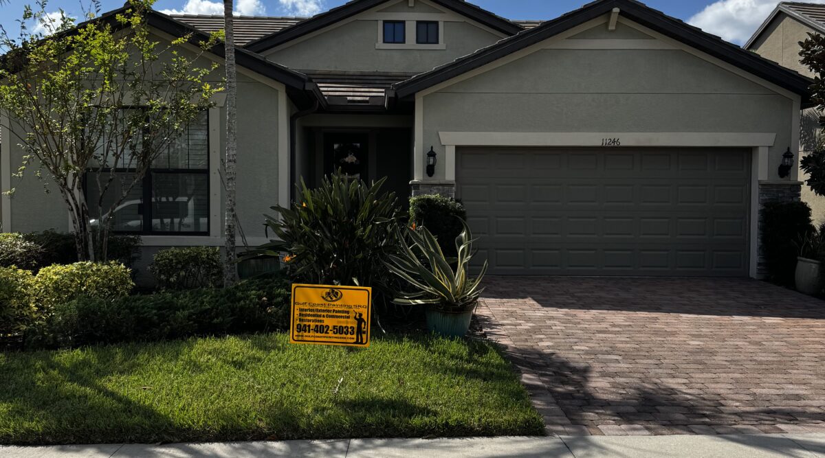 Newly painted one-story house in Sarasota, Florida, showcasing a vibrant exterior finish, with the Gulf Coast Painting SRQ company sign visibly placed in front.