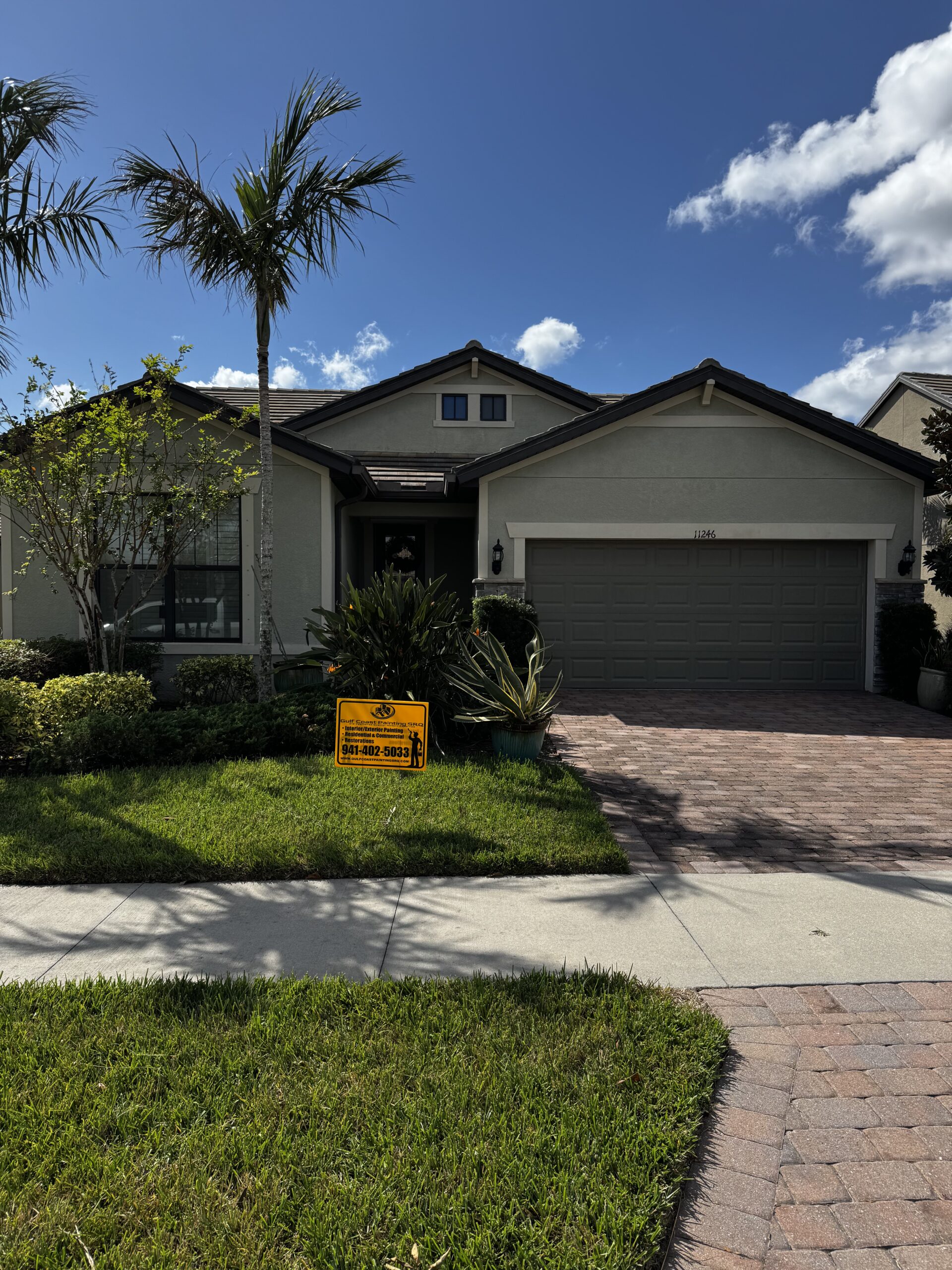 Newly painted one-story house in Sarasota, Florida, showcasing a vibrant exterior finish, with the Gulf Coast Painting SRQ company sign visibly placed in front.